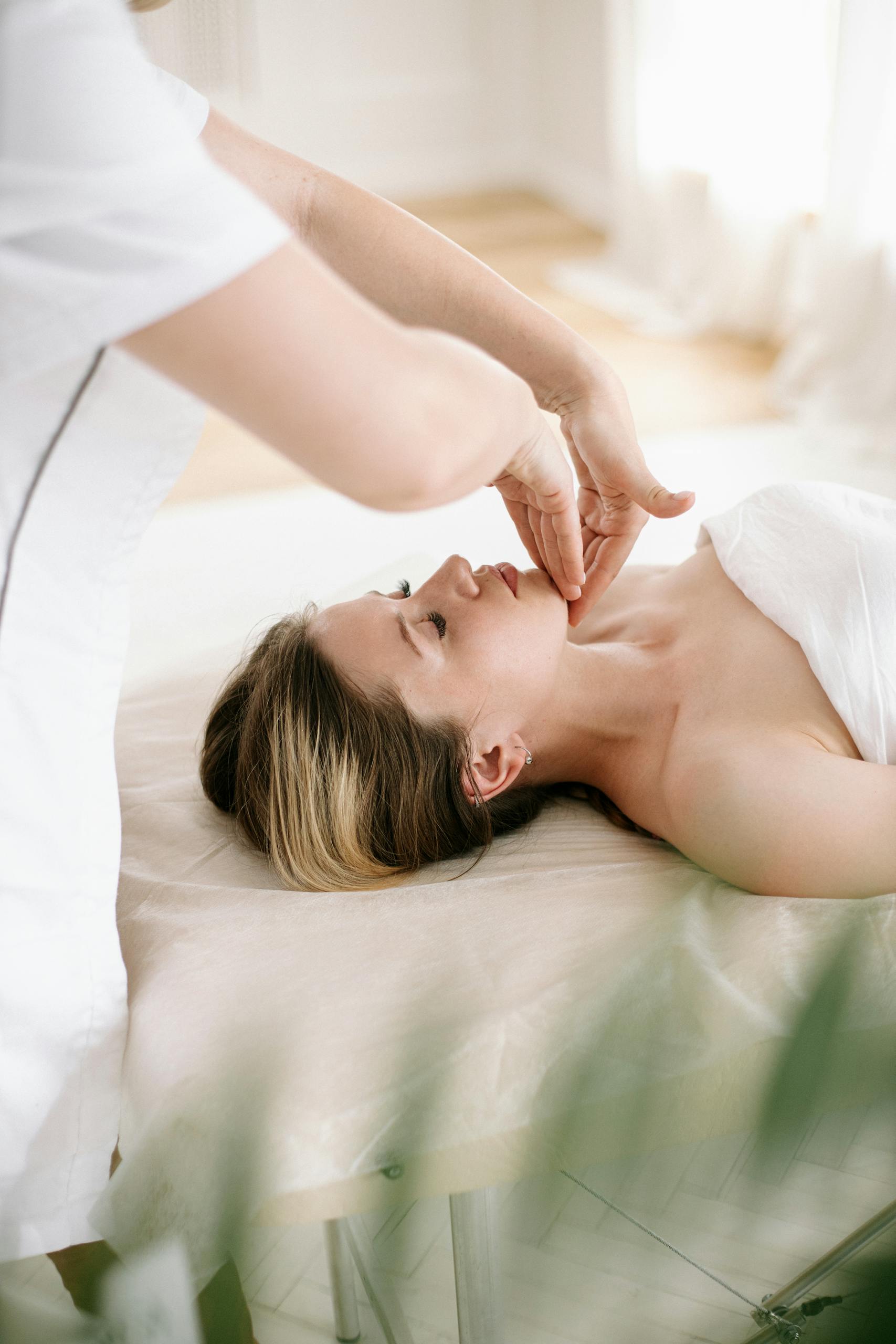 Woman enjoys a soothing facial massage in a serene spa environment, promoting relaxation and skincare.