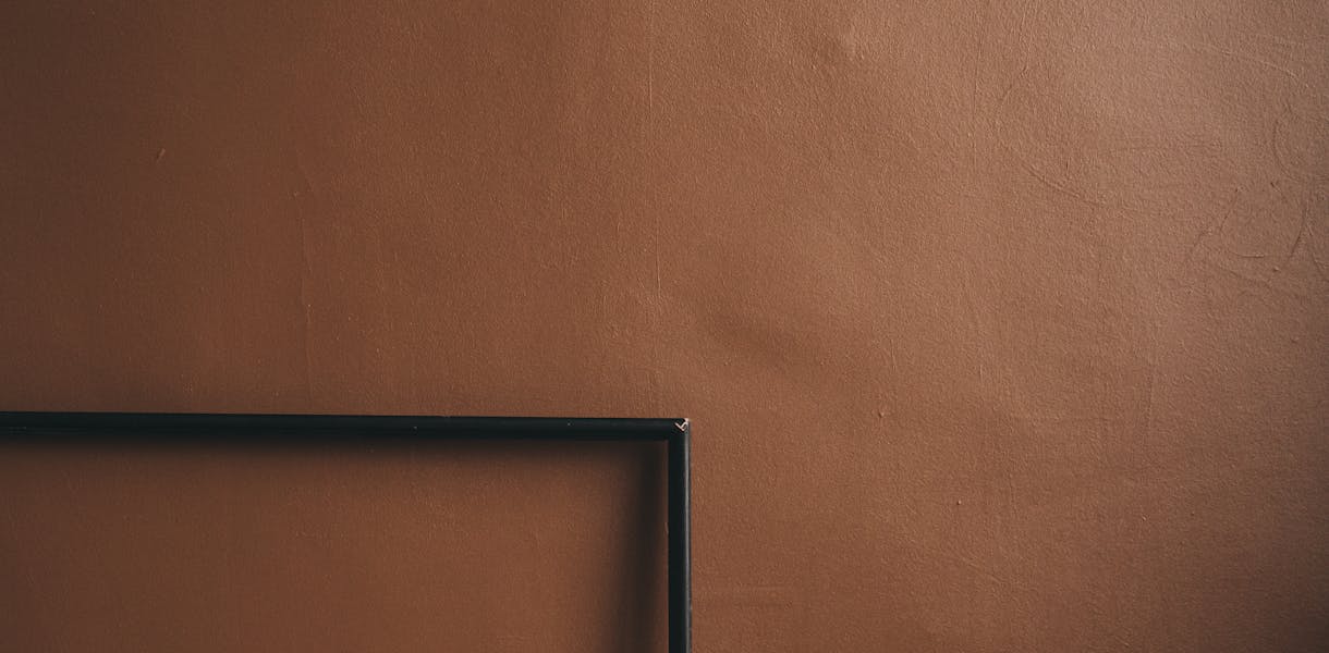 Artistic arrangement of empty wooden frames against a brown wall, showcasing minimalist design.
