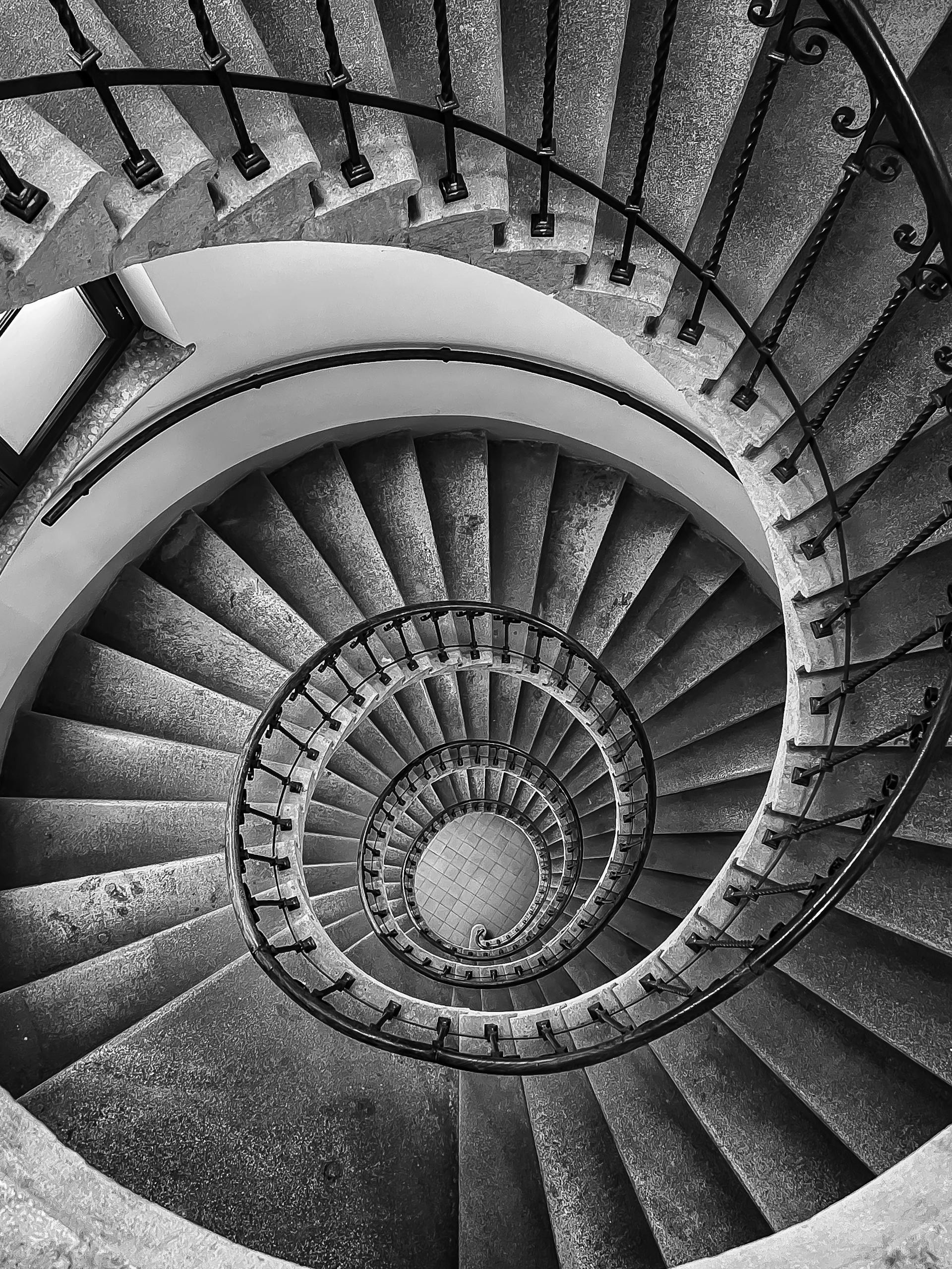 Black and white photo of an intricate spiral staircase with a diminishing perspective in Vienna.