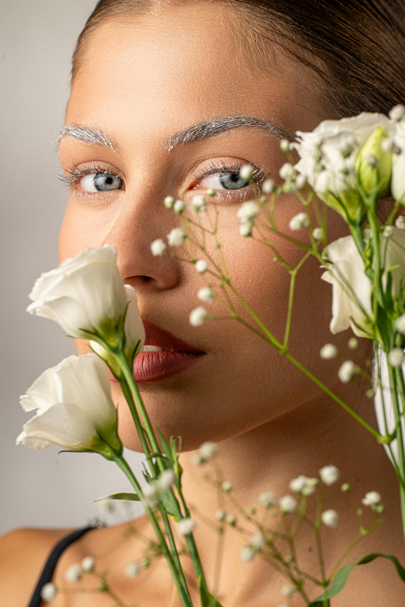 A striking portrait of a woman with white flowers in a studio setting.
